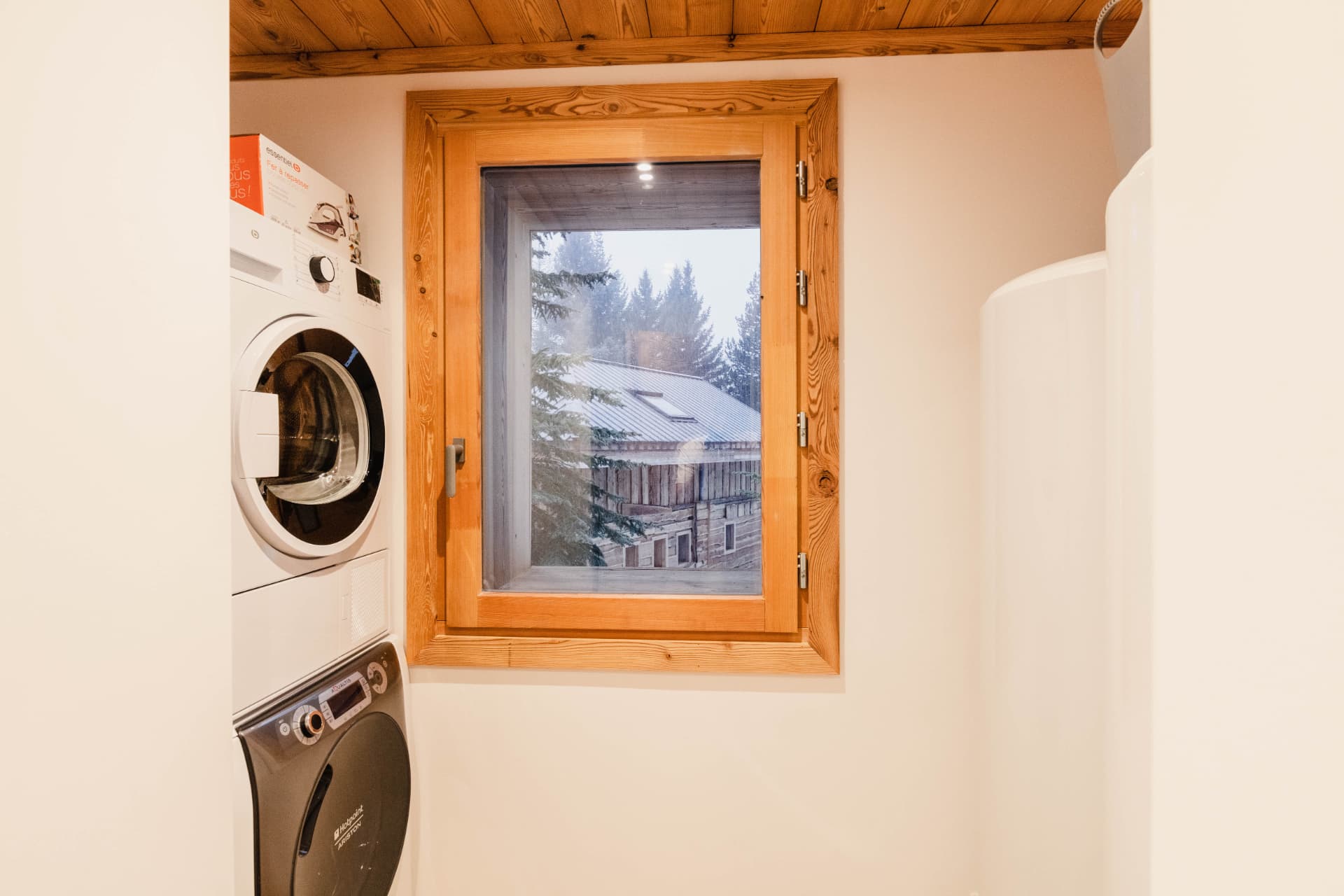 Buanderie du chalet avec lave-linge, sèche-linge et fenêtre sur les sapins