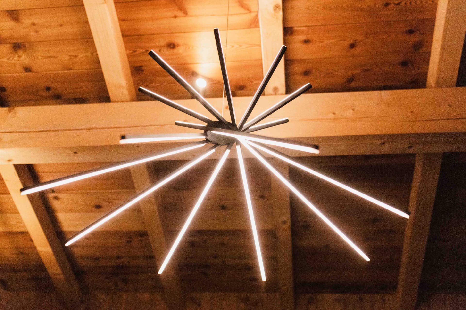 Luminaire contemporain en étoile sous la charpente en bois du chalet