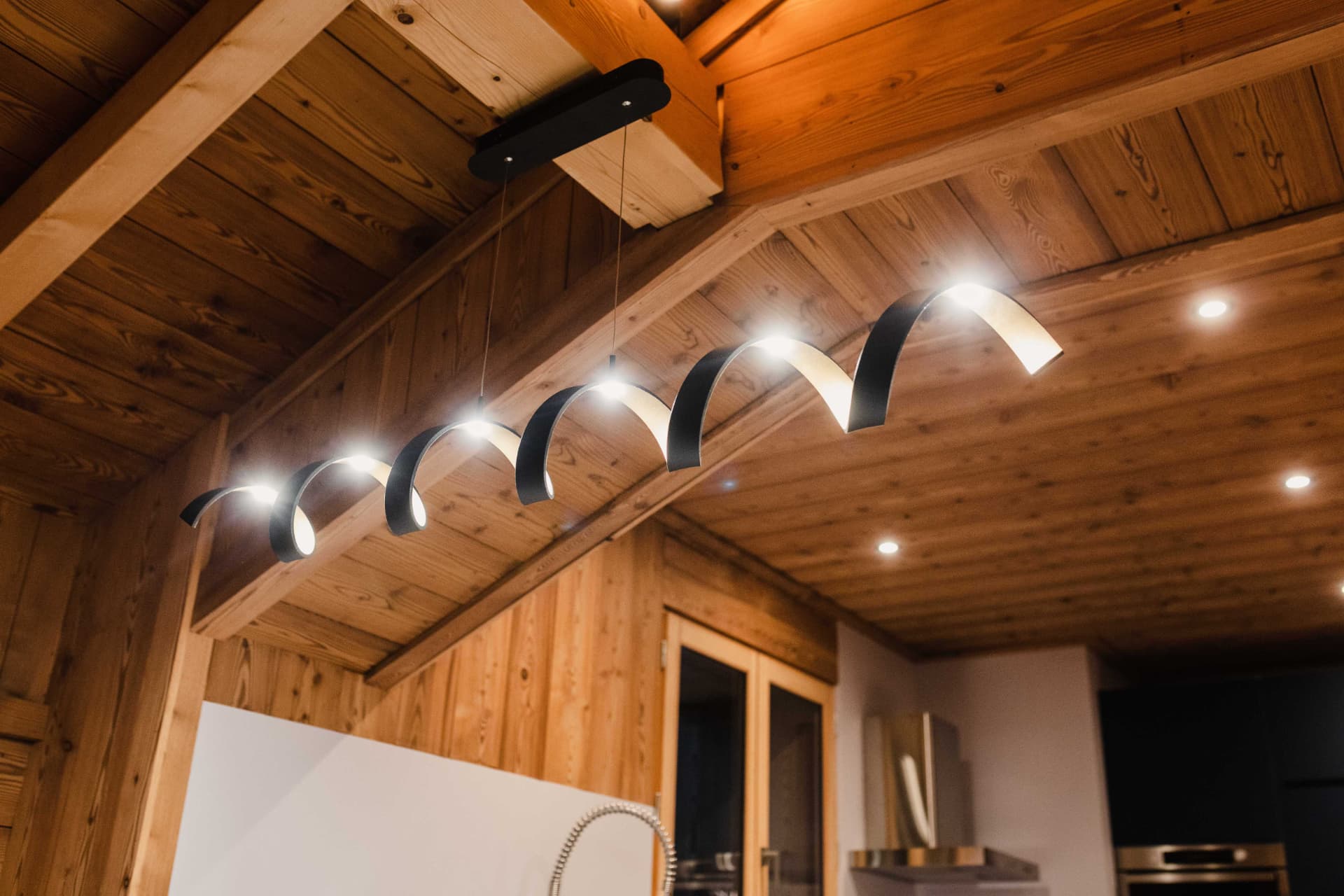 Suspension design au-dessus de l'îlot de cuisine sous les poutres anciennes
